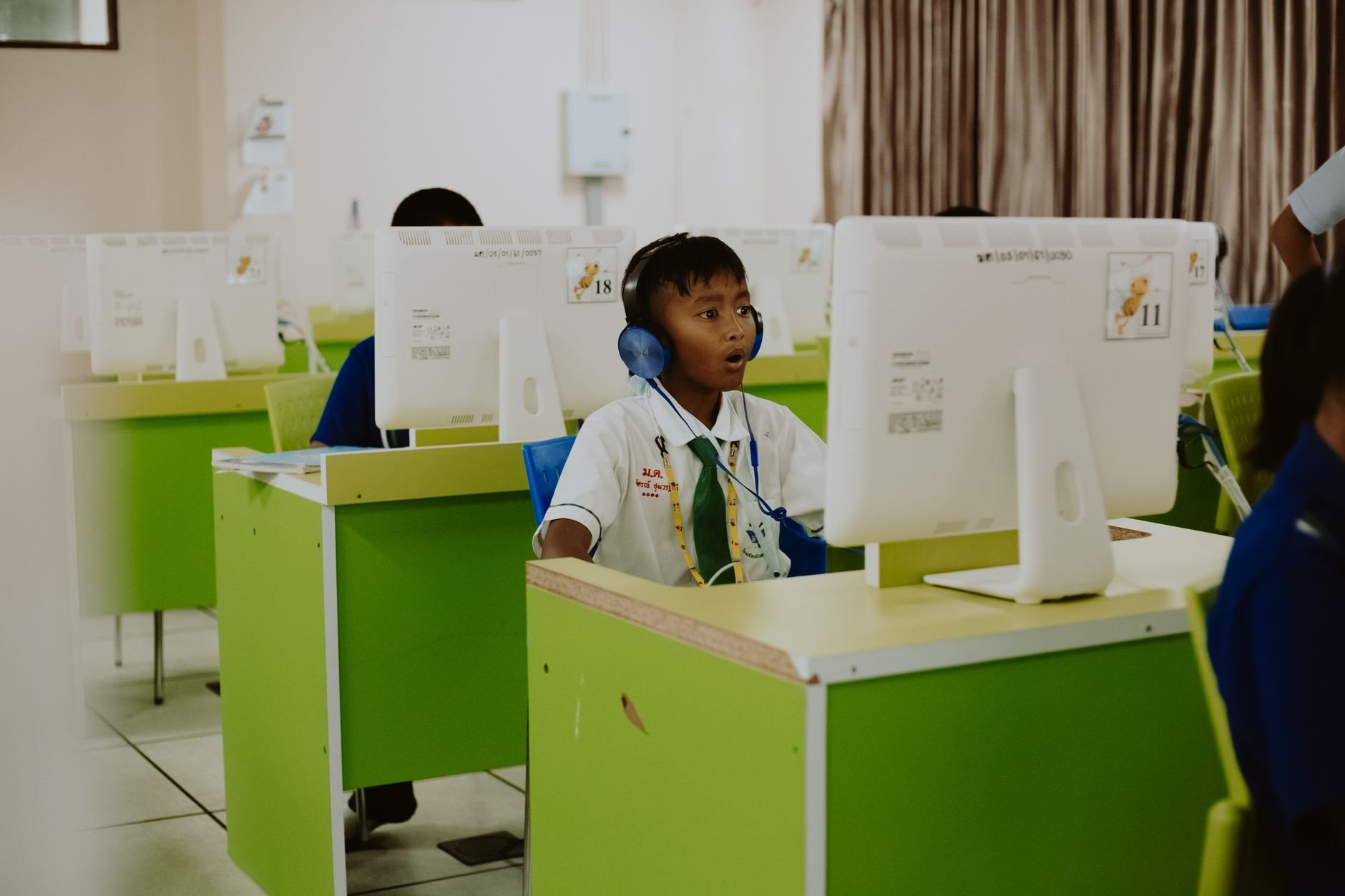 A child in a school computer lab focused on learning with headphones on