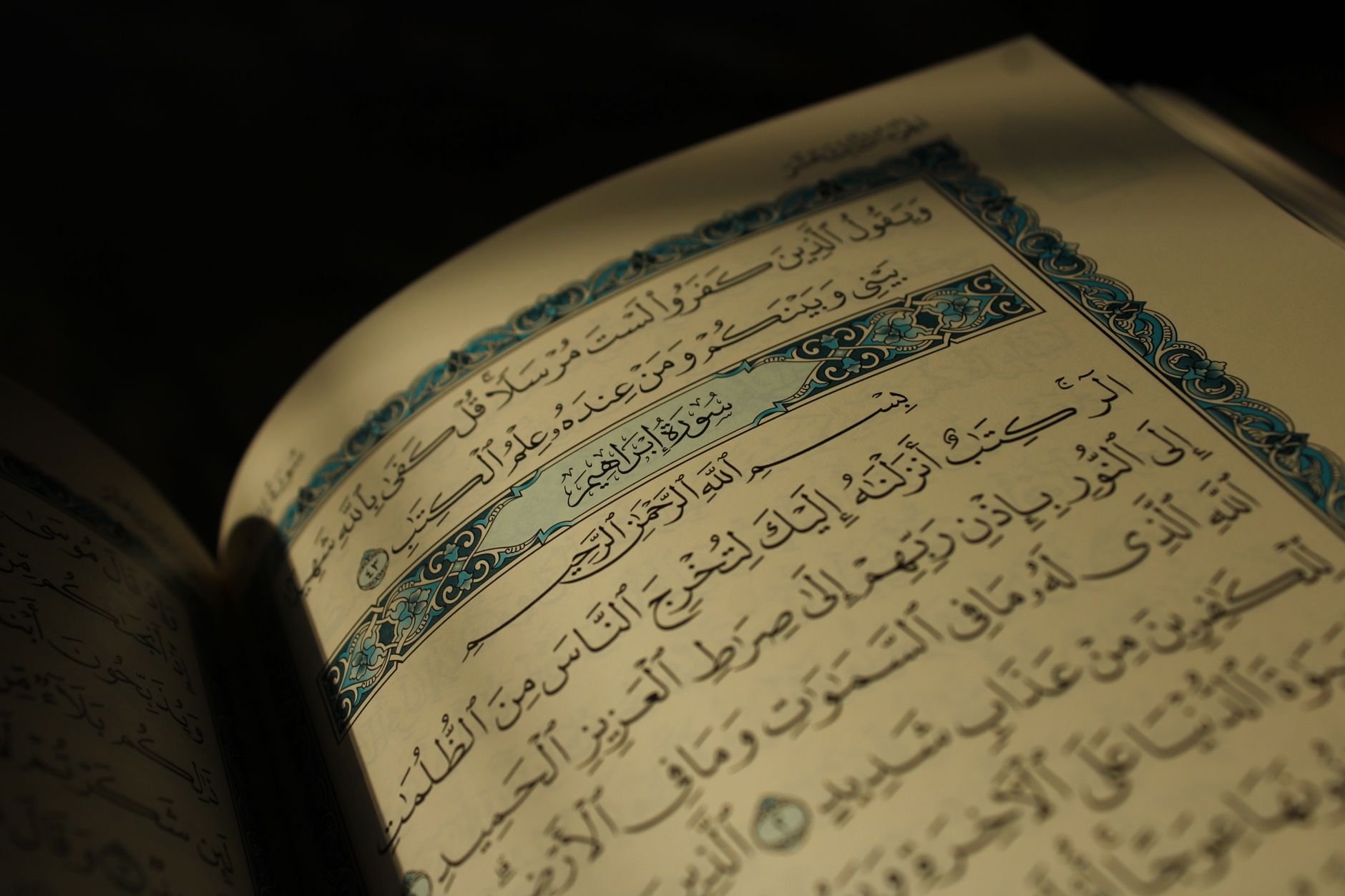 Close-up of an open Quran displaying Arabic calligraphy under warm lighting